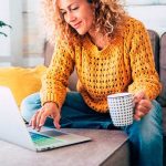 A woman sitting on the couch with her laptop