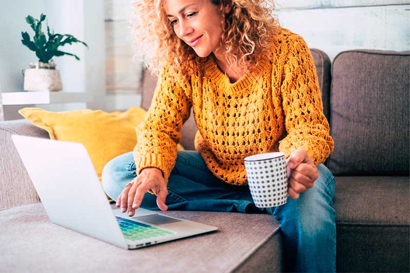 A woman sitting on the couch with her laptop