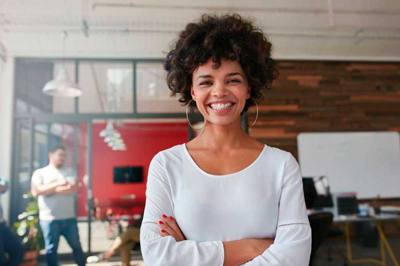 A woman standing in an office with her arms crossed.