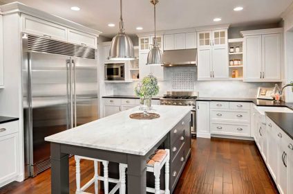 A kitchen with white cabinets and wooden floors