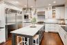 A kitchen with white cabinets and wooden floors
