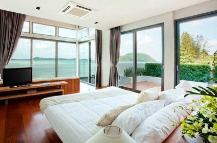 A bedroom with two beds and large windows.